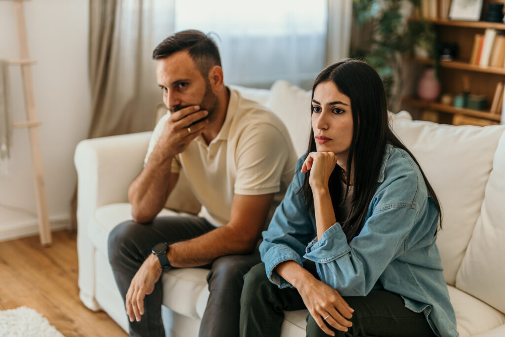Foto decorativa de pareja preocupada sentada en el sofa